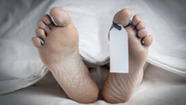 Close-up of the feet of a corpse covered in a sheet; with a blank tag tied on the big toe of the left foot; with an added vignette and copy space