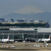 Planes are parked at gates at Tokyo Haneda International Airport as Mount Fuji appears Tuesday, May 4, 2021, in Tokyo. Tokyo and the western metropolises of Osaka, Kyoto and Hyogo, home to about a quarter of Japan's population of 126 million, are under the latest 17-day state of emergency as the variant, detected earlier in Britain, is rapidly spreading among younger people, causing more serious cases. People are discouraged to travel during Japan's 