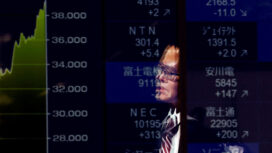 FILE PHOTO: A passerby is reflected on an electronic screen displaying a graph showing recent Japan's Nikkei share average movements and stock prices as the share average hits a record high in Tokyo, Japan February 26, 2024.  REUTERS/Issei Kato/File Photo