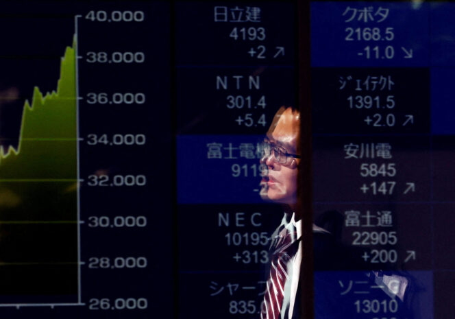 
					FILE PHOTO: A passerby is reflected on an electronic screen displaying a graph showing recent Japan's Nikkei share average movements and stock prices as the share average hits a record high in Tokyo, Japan February 26, 2024.  REUTERS/Issei Kato/File Photo