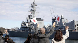 People wave as Japan's Maritime Self-Defence Force destroyer 