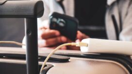 Cropped image of a South Asian man waiting in airport lounge charging his phone using power bank before departure. Focus on the foreground.