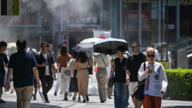 Pedestrians walk under a cooling mister (top L) while sheltering from the sun as the summer heat returns across the country, along a street in the Yuruakucho area of Tokyo on June 16, 2024. (Photo by Richard A. Brooks / AFP)