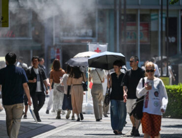 Pedestrians walk under a cooling mister (top L) while sheltering from the sun as the summer heat returns across the country, along a street in the Yuruakucho area of Tokyo on June 16, 2024. (Photo by Richard A. Brooks / AFP)