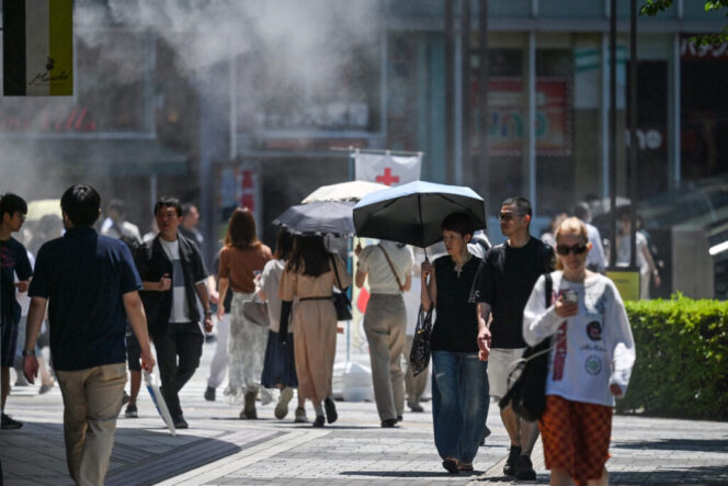 
					Pedestrians walk under a cooling mister (top L) while sheltering from the sun as the summer heat returns across the country, along a street in the Yuruakucho area of Tokyo on June 16, 2024. (Photo by Richard A. Brooks / AFP)