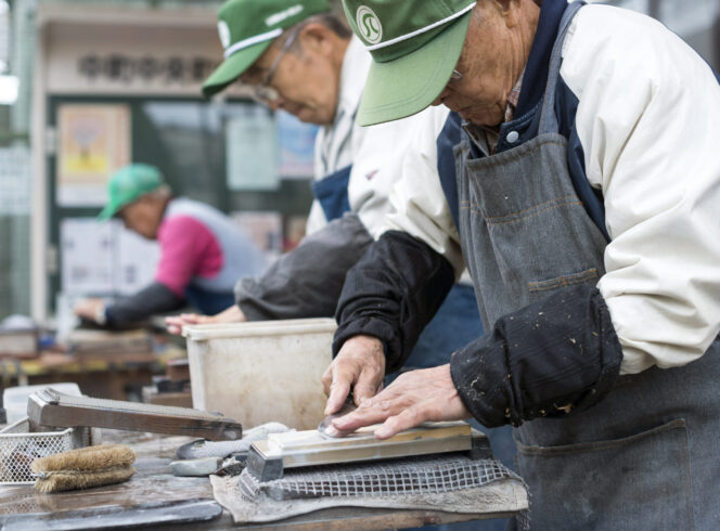 
					Retirees sharpen knives as part of the Silver Jinzai Service in Tokyo, Japan on Dec. 15 2015. The service, which aims to provide light work for the elderly, first came into into existence in 1975. Photographer: Rob Gilhooly