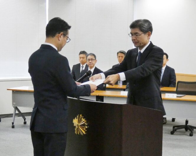 
					National Police Agency Commissioner-General Yoshinobu Kusunoki (right) hands a letter of appointment to Akira Uno, head of the agency's newly created information analysis office, at the agency in Tokyo on Wednesday. | JIJI