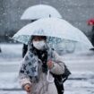 A woman wearing a protective face mask walks on a street in snowfall Tokyo, Japan January 6, 2022