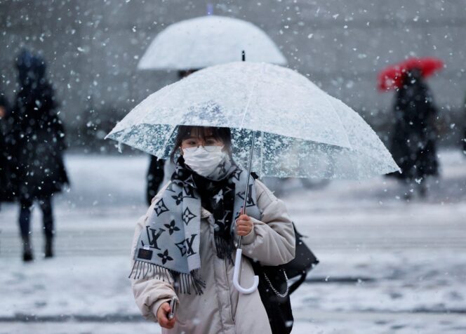 
					A woman wearing a protective face mask walks on a street in snowfall Tokyo, Japan January 6, 2022