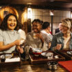 Young women laughing on night out, food and drink, bonding, carefree