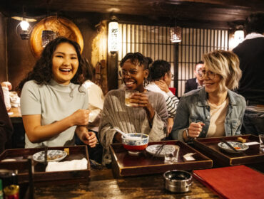 Young women laughing on night out, food and drink, bonding, carefree