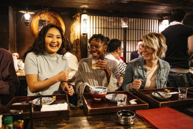 
					Young women laughing on night out, food and drink, bonding, carefree