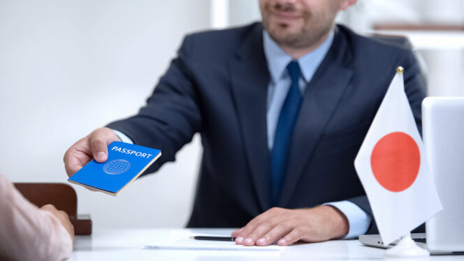 
					Japan consular officer giving passport to young woman, student visa approval